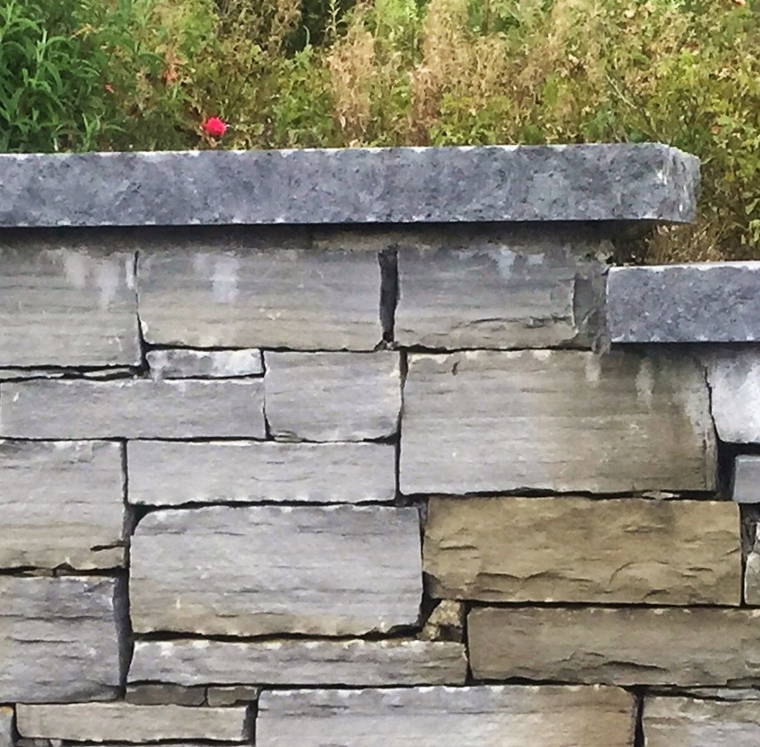 Dressed limestone rock face complimenting a dry grey sandstone wall