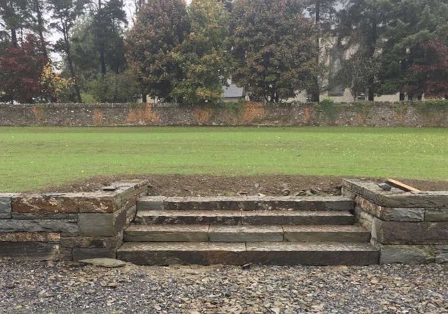 Large rock armour retaining wall with hand dressed grey/brown sandstone steps