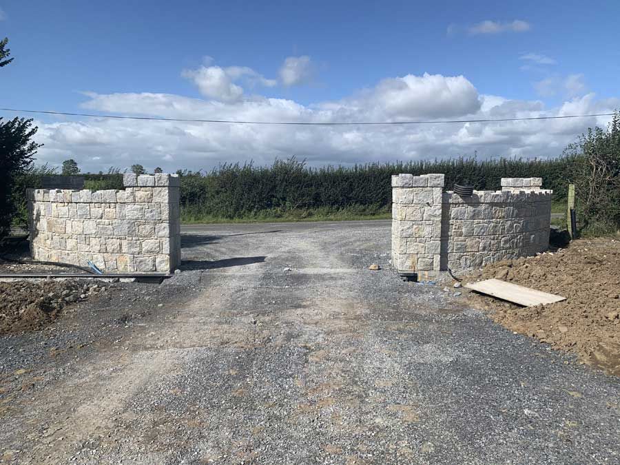 Grey granite entrance with some brown shades enhanced with large dressed corner stones and cock & hen capping