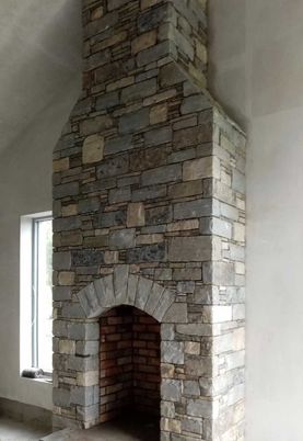 Mixed sandstone internal fireplace with handcrafted grey sandstone arch