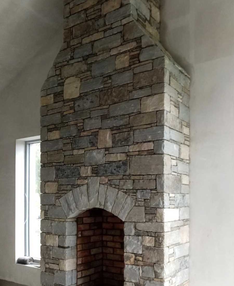 Mixed sandstone internal fireplace with handcrafted grey sandstone arch