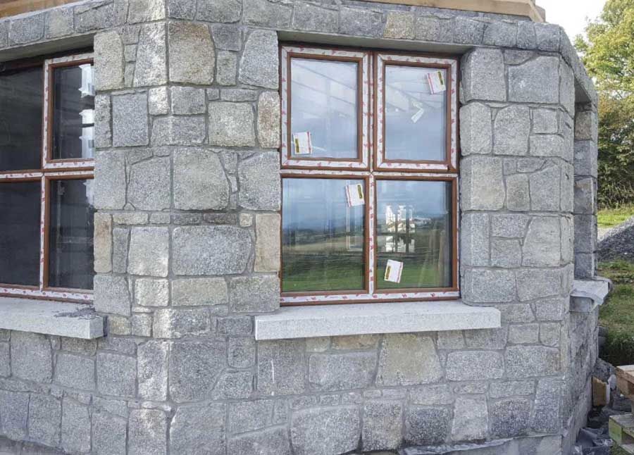 Grey granite laid in courses complimented with grey granite window cills