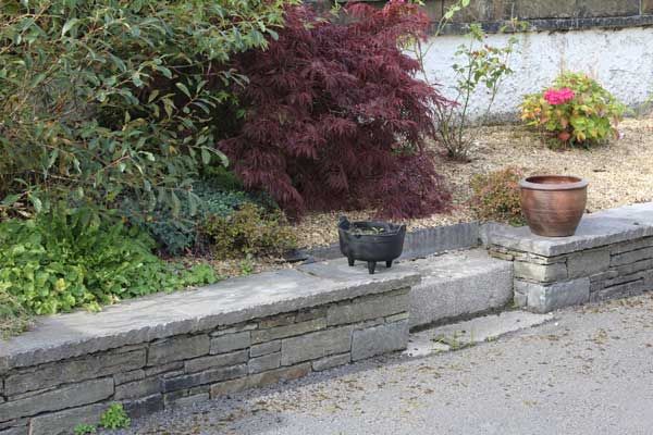 Grey sandstone wall with dressed limestone wall capping