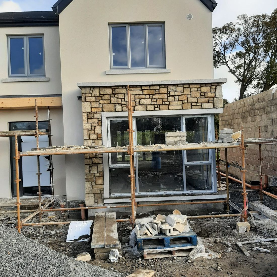 Cream thin wall cladding complimented with grey granite window surrounds and capping 