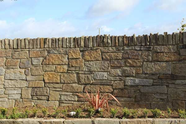 Brown sandstone wall capped with soldier coursing