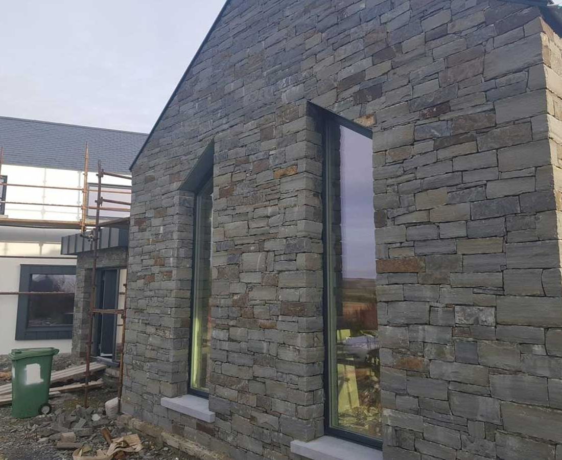 Grey sandstone laid traditionally featuring limestone window cills